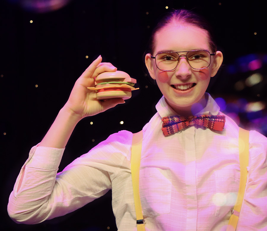 Young person wearing a bowtie and holding a plastic hamburger in her hand